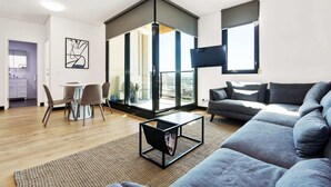 A modern living room with a grey sofa, a coffee table, and a dining area with chairs and a table. - Swainson on Synagogue (Adelaide)