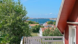 Eine Küstenstadt mit roten Dächern, einem weißen Zaun und Blick aufs Meer.