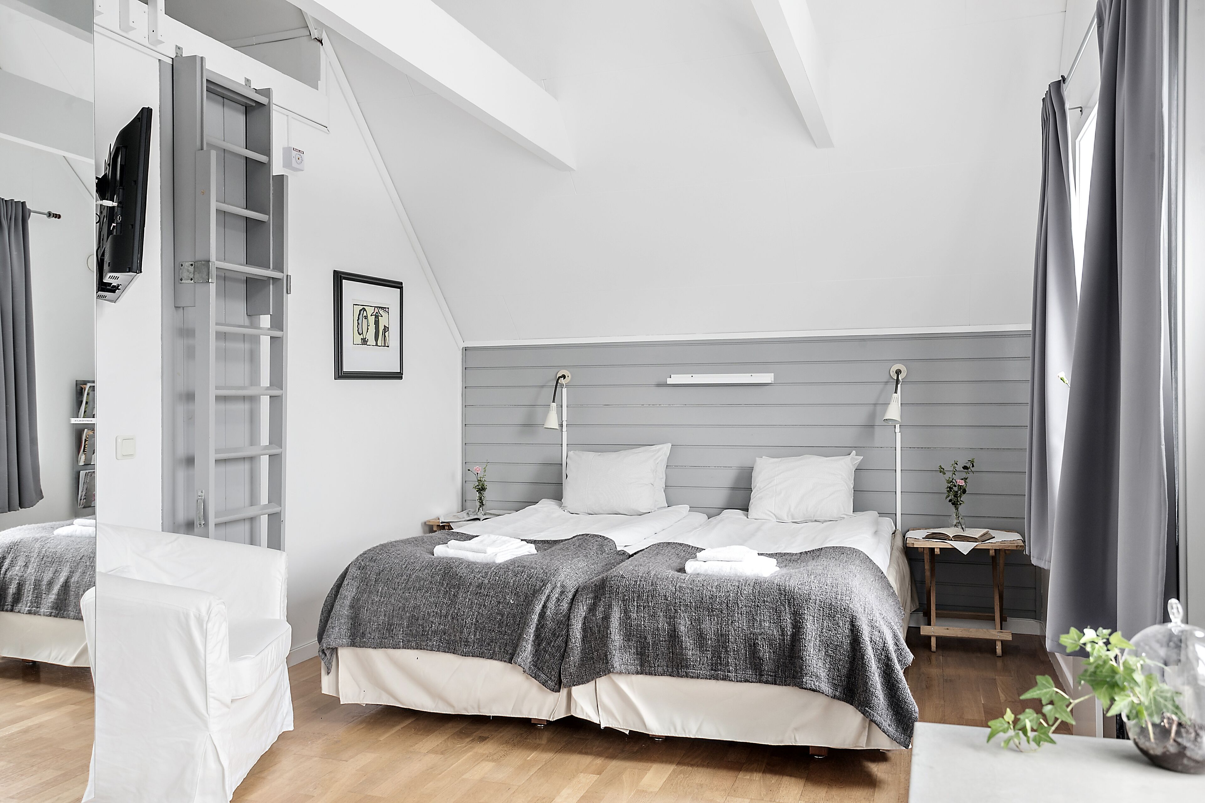 Ein modernes Schlafzimmer mit Hochbett, Nachttisch und einer kleinen Pflanze.