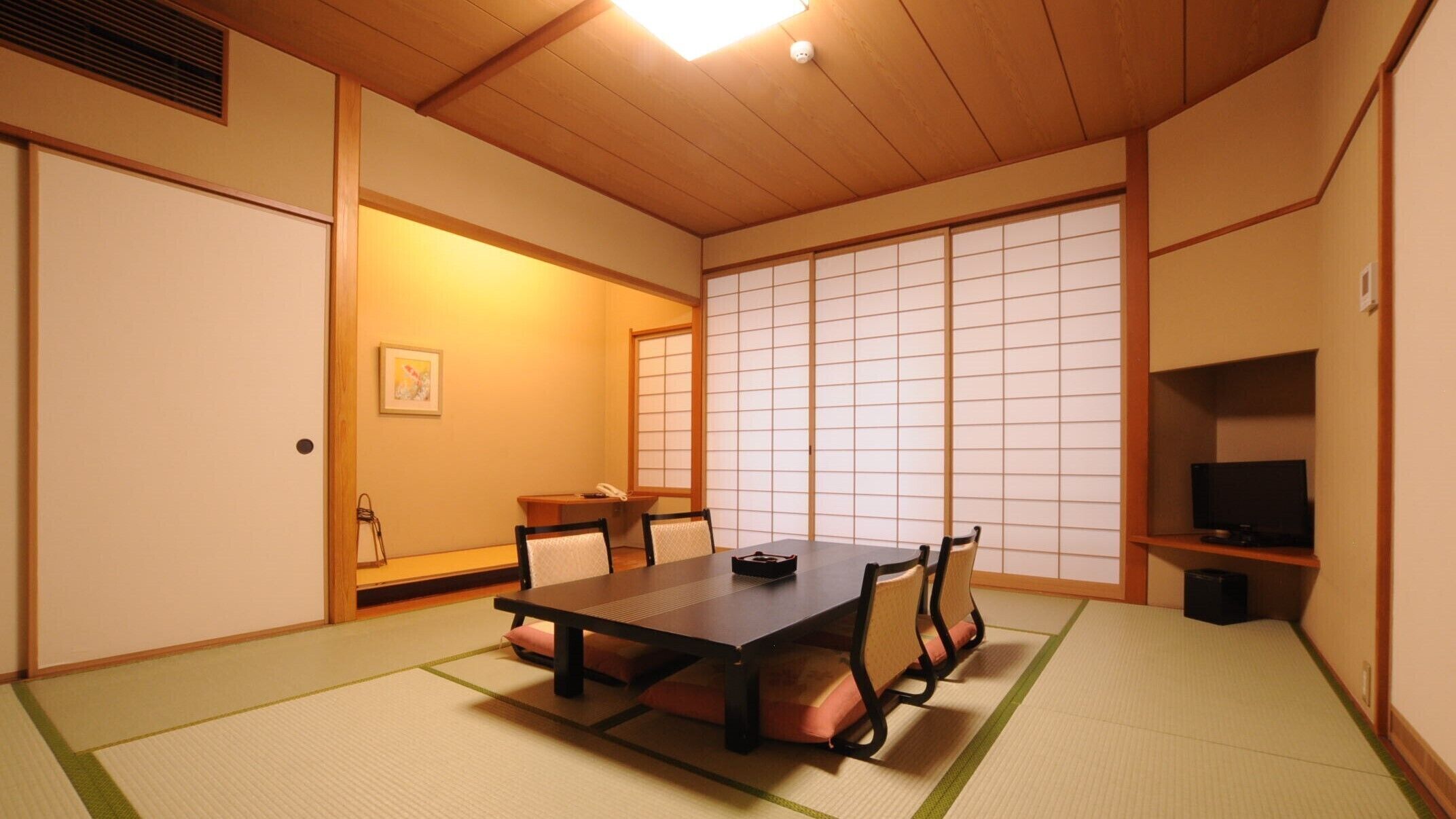 Una habitación japonesa tradicional con suelo de tatami, una mesa baja y puertas correderas.
