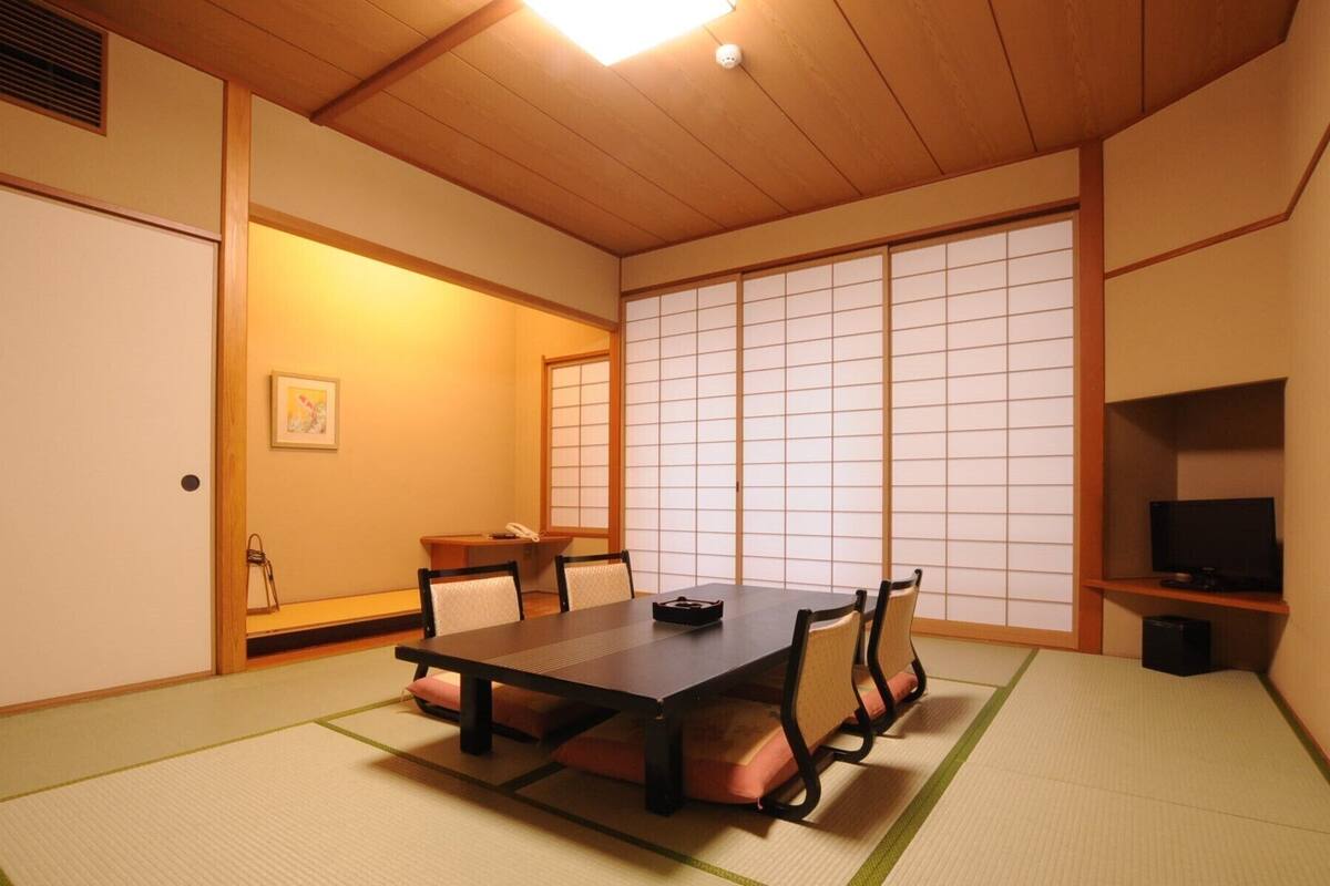 Perinteinen japanilainen huone, jossa on tatamimatto, matala pöytä ja liukuvat ovet.