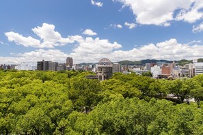 Un paisaje urbano con un edificio destacado que posee una estructura cúpula singular, rodeado de árboles verdes y frondosos.