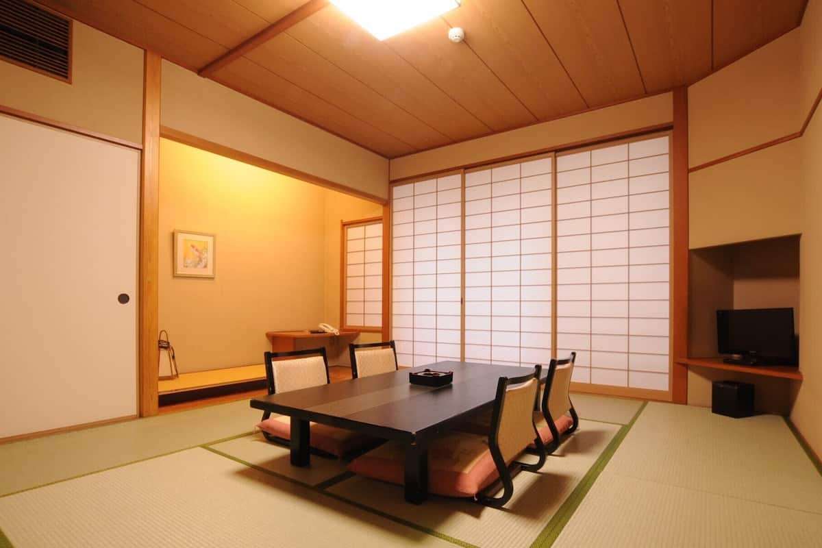 Una habitación japonesa tradicional con suelo de tatami, una mesa baja y puertas correderas.