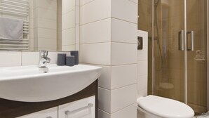 A modern bathroom with a white sink, vanity, and a glass-enclosed shower. - Victus Apartamenty - Chopin 2 (Sopot)