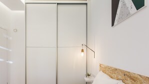 Ein Schlafzimmer mit einem Bett, einem Nachttisch, einer Wandlampe und einer Schiebetür zum Kleiderschrank.