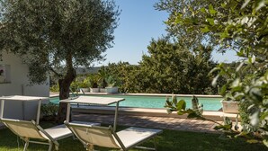 A poolside area with two lounge chairs and a table, surrounded by greenery and a clear blue sky. - Charming Trulli with Pool for 8 people in Monopoli’s countryside (Monopoli)