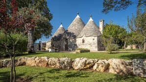 A stone building with conical roofs, surrounded by a stone wall and greenery. - Charming Trulli with Pool for 8 people in Monopoli’s countryside (Monopoli)