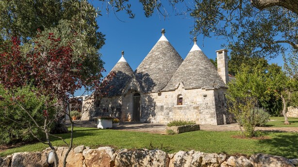 A stone building with three conical roofs, surrounded by a well-maintained garden and stone walls. - Charming Trulli with Pool for 8 people in Monopoli’s countryside (Monopoli)