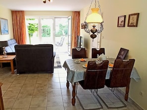 Un comedor con una mesa dispuesta para cuatro personas, un sofá y un televisor al fondo.