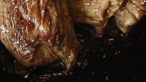 Een close-up van een gebakken steak, versierd met groenten en rode uien.