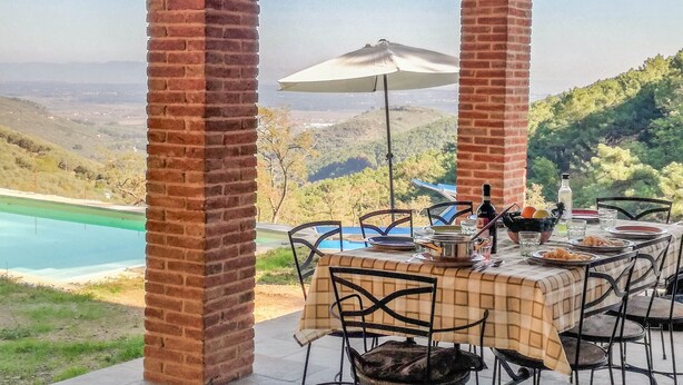 A covered outdoor dining area with brick pillars, a table set with plates, glasses, and a bottle, overlooking a scenic landscape with a pool and hills. - House with private pool and panoramic views 20km from Pisa, 1km from village (Buti)
