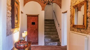 A hallway with a wooden door, a staircase, a chandelier, and a radiator. - House with private pool and panoramic views 20km from Pisa, 1km from village (Buti)