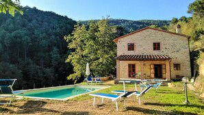 A stone building with a red-tiled roof, a swimming pool, and lounge chairs. - House with private pool and panoramic views 20km from Pisa, 1km from village (Buti)