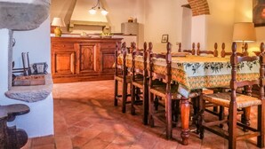 A dining area with a long wooden table and chairs, a rustic brick archway, and a kitchen in the background. - House with private pool and panoramic views 20km from Pisa, 1km from village (Buti)