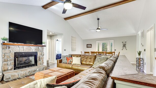 A spacious living room with a stone fireplace, leather sofa, and a long dining table. - Home < 2 Mi to Mtn Greens Golf, Massanutten Ski! (Mcgaheysville)
