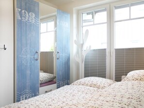 A bedroom with a bed, a wardrobe, and a window with blinds.