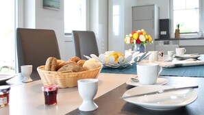 Een ontbijtsetting met een broodmand, een bloevas en ontbijtspullen op een tafel.