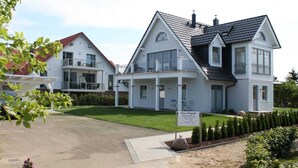 Een groot, twee verdiepingen tellend huis met een balkon en een bordje dat het een gastenverblijf aangeeft.