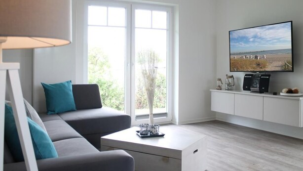 Een moderne woonkamer met een bank, salontafel, televisie en een raam met uitzicht op de omgeving.