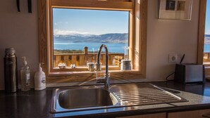 A kitchen with a large window offering a view of a lake and mountains. - Brekka - Stunning Country & Ocean View Location, Yet Close To Reykjavik (Akranes)