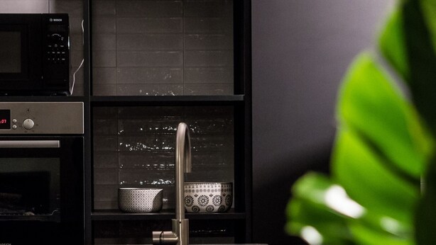 A modern kitchen with a Bosch microwave, a sink, and a shelf with patterned dishes. - Le Logge 2 apartment (Parma)