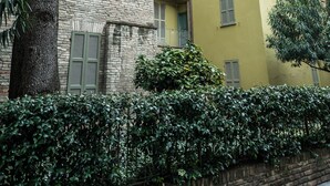 A multi-story building with a brick facade and a yellow building adjacent to it. - Le Logge 2 apartment (Parma)