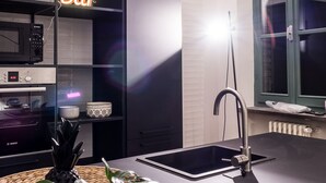 A modern kitchen with a black countertop, a sink, a Bosch oven, and a neon 'Bar' sign. - Le Logge 2 apartment (Parma)