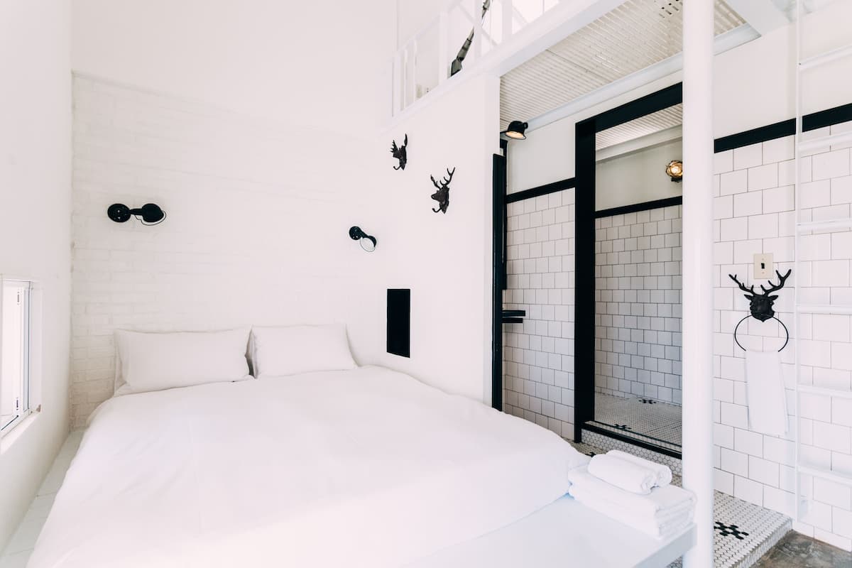 A white brick wall with mounted animal horns and a black metal bed frame.
