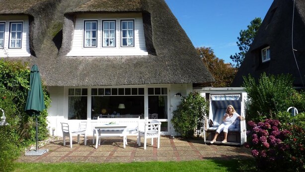 A house with a thatched roof, white exterior walls, and a covered patio with a table and chairs. - House Tondernhüs, Germany (Sylt-Ost)