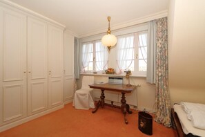 Une chambre à coucher comprenant un lit, un bureau, une chaise, un radiateur et une armoire.