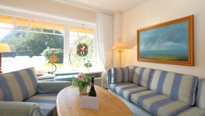 A cozy living room with a striped sofa, a wooden coffee table, and a painting on the wall. - House Tondernhüs, Germany (Sylt-Ost)