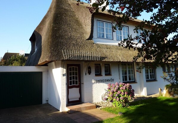 Un bâtiment traditionnel, de couleur blanche, avec un toit de chaume et une enseigne indiquant « FONDERNHS ».