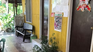 A yellow building with a door labeled '5', a bench, and a poster on the wall. - Oasis Resthouse (San Agustin)