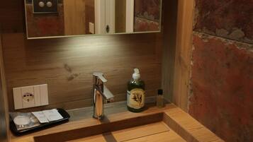 A bathroom with a wooden vanity, a mirror, and a bottle of hand soap.
