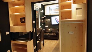 A compact living space with wooden cabinetry, a leather sofa, and a television. - Michele Guest House (Pisa)