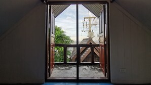 A room with a large sliding door leading to an outdoor area with a view of a building and a utility pole. - Baan Lanna Resort (Chonburi)