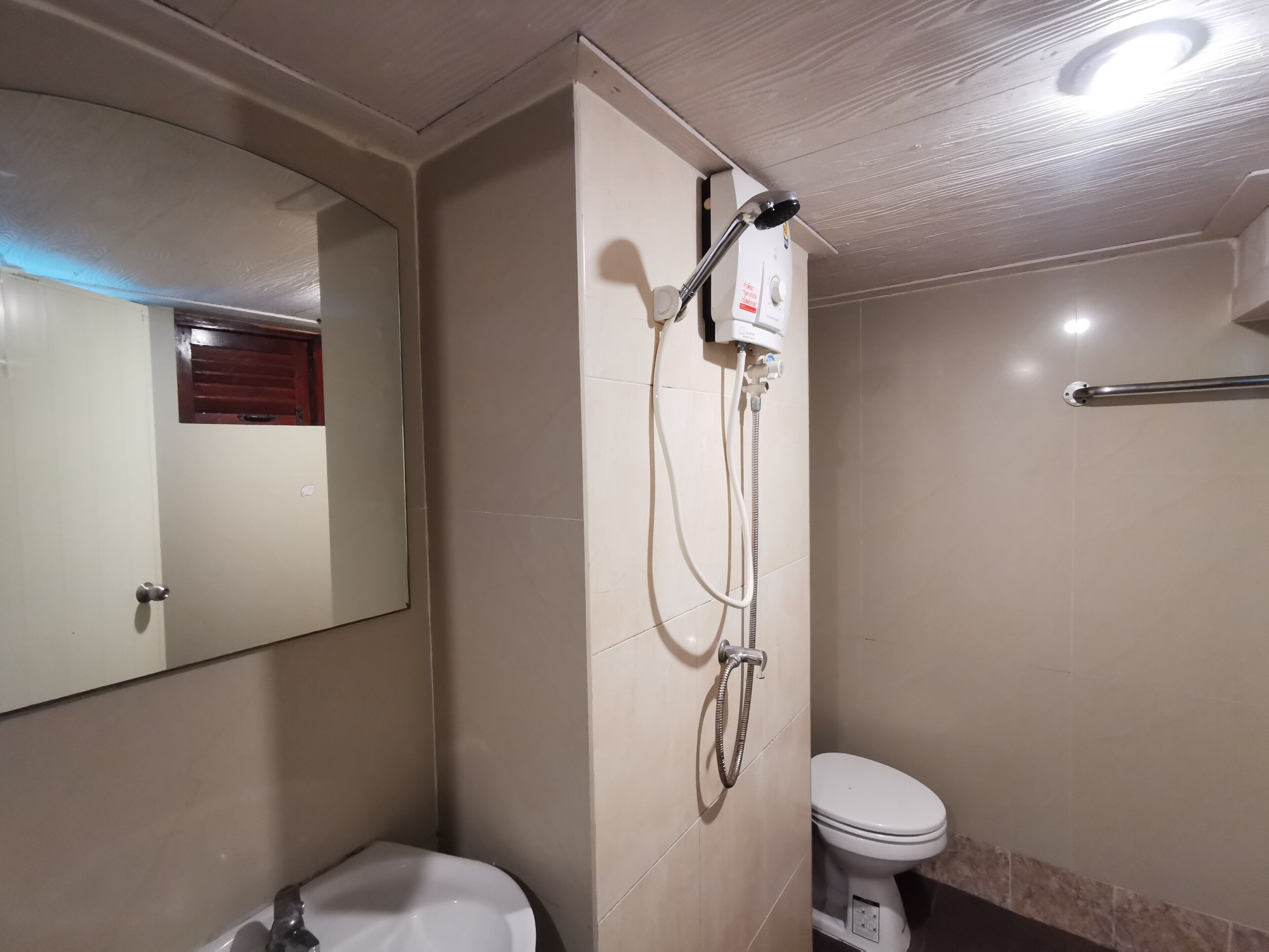 A bathroom with a toilet, a sink, a shower, and a mirror.