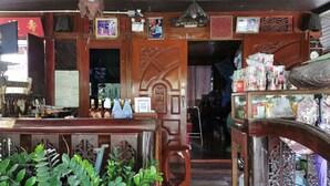 A traditional wooden shop with a wooden counter, various items on display, and a door leading to another room. - Baan Lanna Resort (Chonburi)
