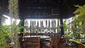 A wooden dining area with a round table and chairs, surrounded by potted plants and a wooden fence. - Baan Lanna Resort (Chonburi)