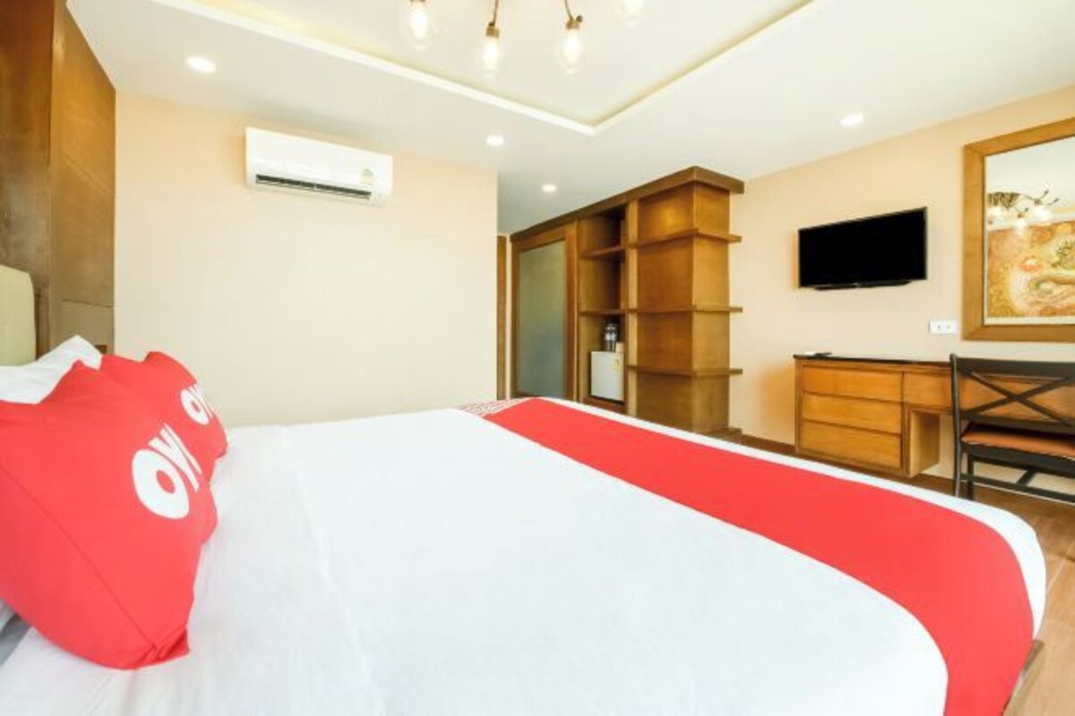 A hotel room with a bed, a TV, a desk, and a wardrobe.