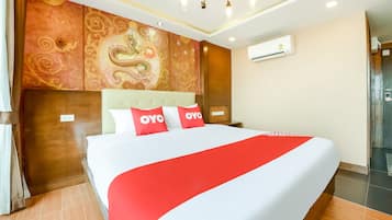 Ein Hotelzimmer mit einem großen Bett, rot-weißer Bettwäsche, einer Wand mit einem Drachenmuster und einer Klimaanlage.