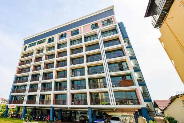 A multi-story hotel with a modern design, featuring balconies on each floor, a ground-level parking area, and a visible restaurant on the ground floor. -  OYO 458 Nakorn Siam Boutique (Pattaya)
