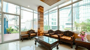 Una habitación amplia con ventanas grandes, una mesa de centro de madera y cómodos sofás de madera decorados.