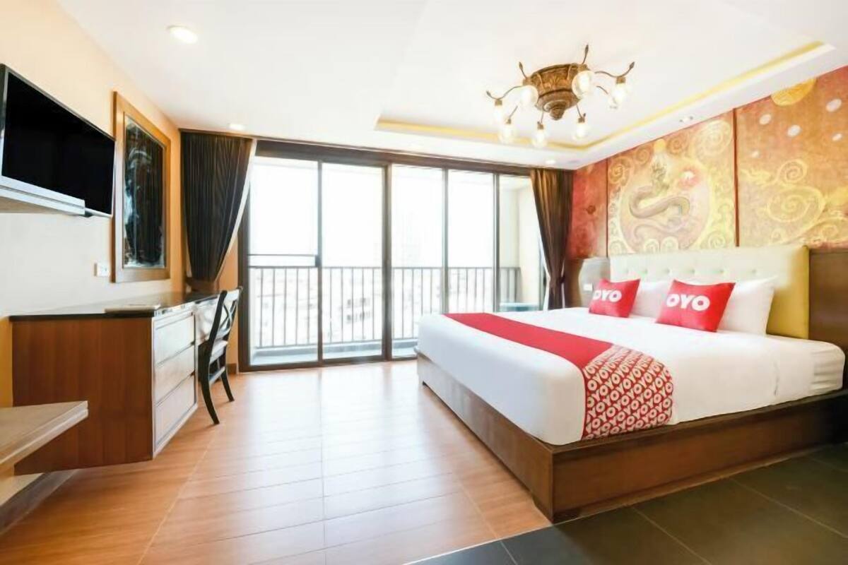 A hotel room with a bed, a desk, a TV, and a balcony.