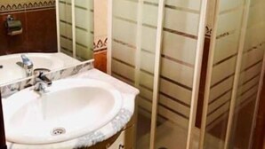 Une salle de bain avec un lavabo en marbre, un miroir et une cabine de douche en verre.