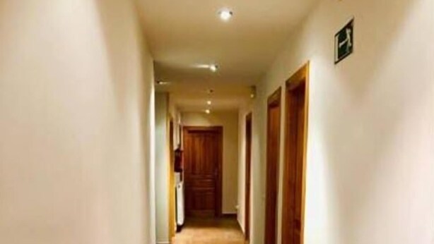Un long couloir étroit, doté d’un sol carrelé et de portes en bois d’un seul côté.