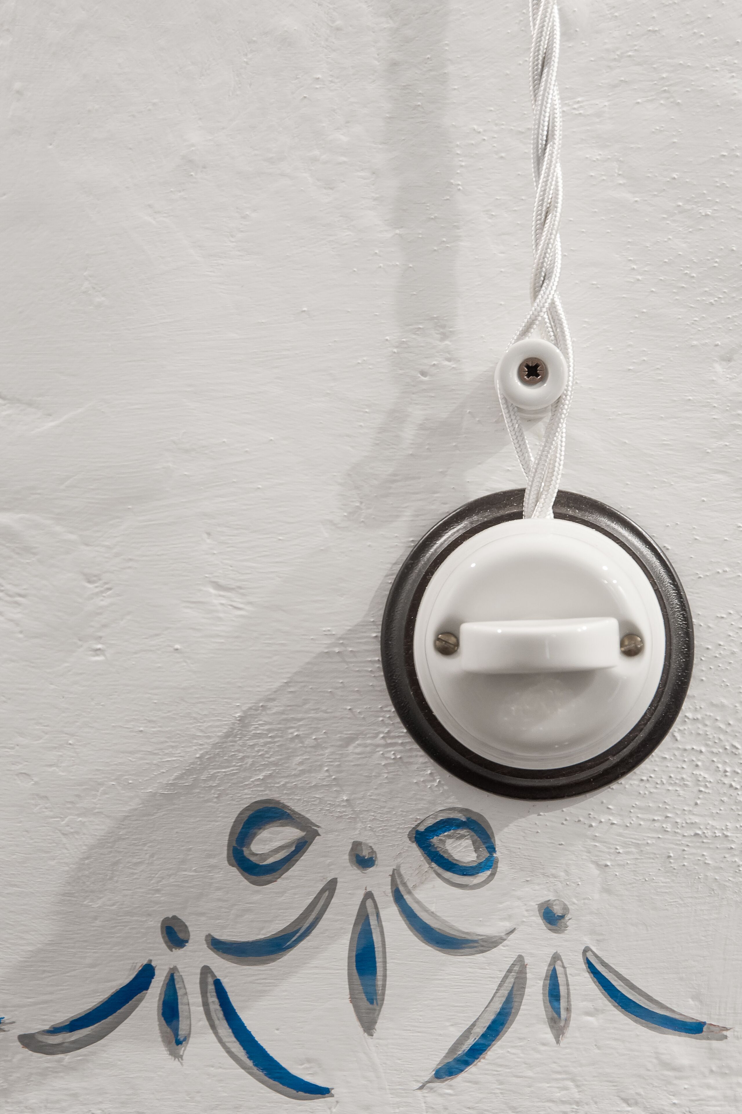 A white wall with a white object hanging from a white cord.