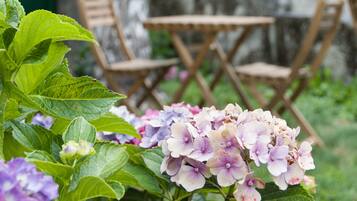 En have med hortensia og træstole.