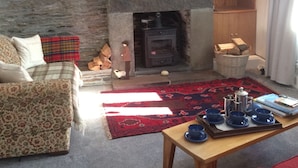 A cozy living room with a stone fireplace, a flat-screen TV, and a sofa.