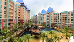 A resort with multiple high-rise buildings, a central water feature with a ship, and palm trees. - Grande Caribbean Resort (Pattaya)